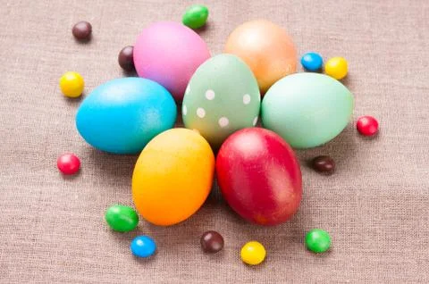 Group of colorful Easter eggs and colored candies lying on linen fabric cloth Foto stock