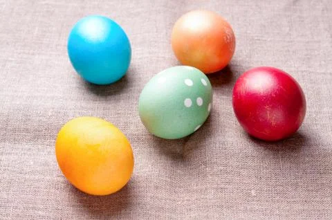 Group of colorful Easter eggs lying on linen fabric cloth close up Stock Photos