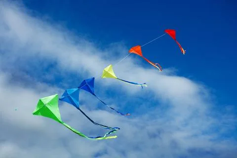 Group of colorful kites fly on the string over blue sky Stock Photos