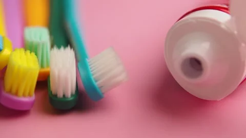 Group of colorful toothbrushes and toothpaste tube on pink background. Stock Footage 331934581