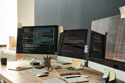 Group of computer screens with coded data standing on wooden table Stock Photos