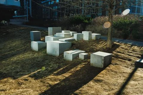 Group of concrete blocks placed on grass with a tree nearby in an urban lan.. 스톡 사진
