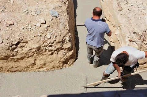 Group of construction workers spreading freshly poured concrete mix Stock Photos