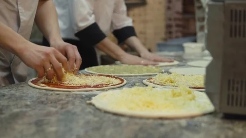 A group of cooks in the form of evenly put cheese on pizza dough circles. Stock Footage 105809215