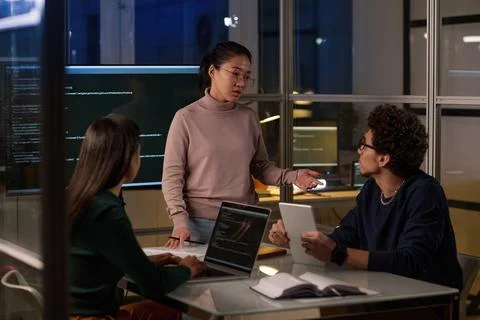 Group of Coworkers Correcting Code In Evening Stock-Fotos