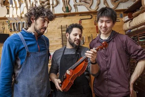 Group of craftsmen violinmakers testing a new violin Foto stock