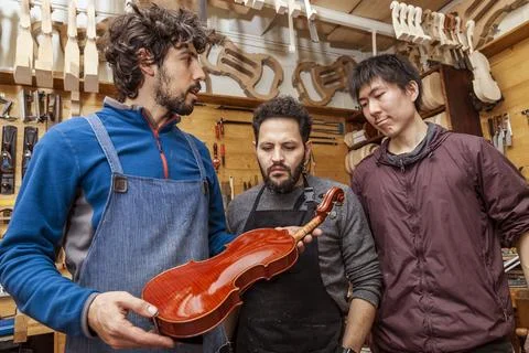 Group of craftsmen violinmakers testing a new violin Stock Photos