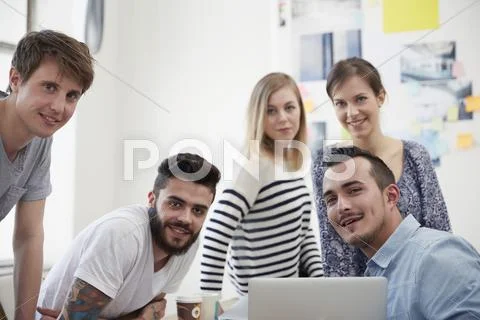Group Of Creative Professionals With Laptop At Table