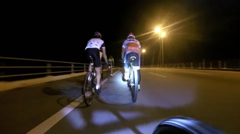 Group cycling at night on a highway Stock Footage