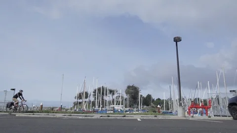 A group of cyclists cross in front of a pier with docked boats Stock Footage 91276785