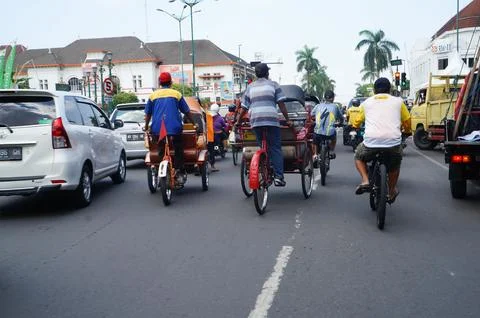 A group of cyclists, rickshaws driving between cars on the street Stock Photos