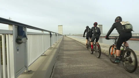 A group of cyclists rides over a trough bridge 스톡 동영상 219893459