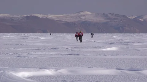 A group of cyclists riding a bicycle across a frozen lake Video stock 81207352