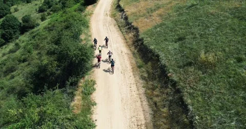 Group of cyclists riding on a dirt path through a scenic rural area Stock Footage 311589002