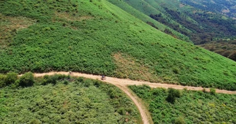 Group of cyclists riding on a dirt path through a scenic rural area Stock Footage 312099773