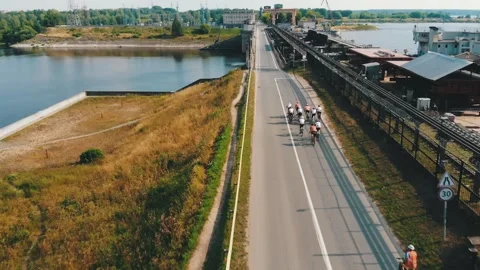 Group of cyclists team ride on bridge over river. Aerial shot of bicycle race Video stock 240750442