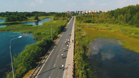 Group of cyclists team ride on bridge over river. Aerial shot of bicycle race Video stock 240750456