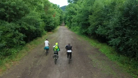 Group of cyclists team ride down gravel mountain road in national park Stock Footage 232846256