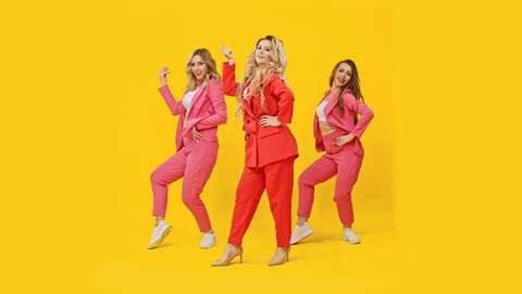 Group dancers of a girl in pink jackets actively dance on a yellow background - Stock Footage
