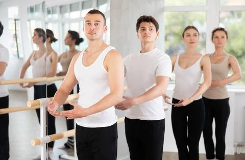 Group of dancers stand in first position at barre Stock Photos