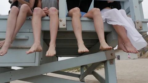 Group dangle feet at tower on beach Stock Footage 112897130