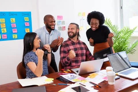 Group of developers celebrate successful launch of new mobile app in office Stock Photos