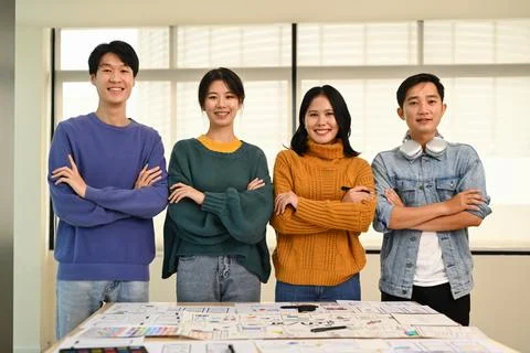 Group of developers standing with arms crossed and smiling to camera at creative Stock Photos
