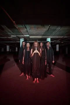 A group of devil worshipers lined up together while holding a candle in the.. Stock Photos