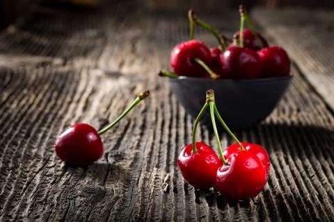 Group dew-covered cherries on old wooden table Stock Photos