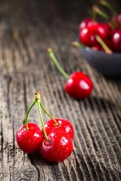 Group dew-covered cherries on old wooden table Stock Photos