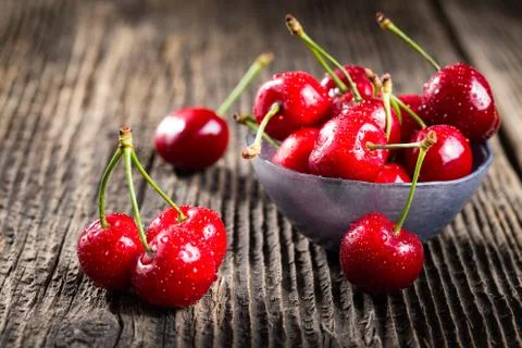 Group dew-covered cherries on old wooden table Stock Photos