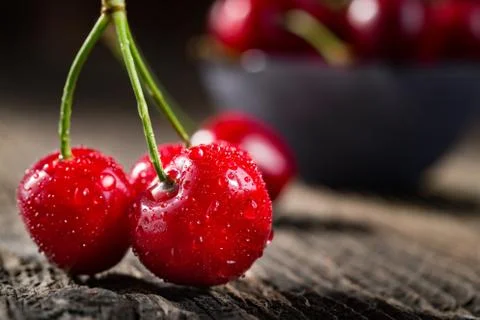 Group dew-covered cherries on old wooden table Stock Photos