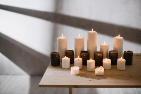 A group of different sized candles stands on a simple wooden table. Foto stock