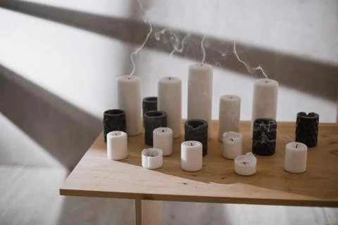 A group of different sized candles stands on a simple wooden table. Foto stock