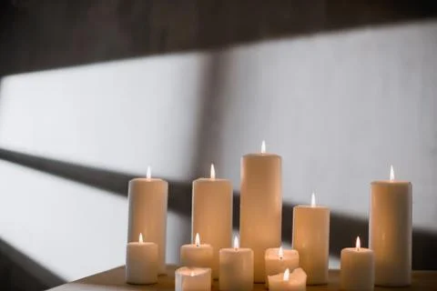 A group of different sized candles stands on a simple wooden table. Foto stock