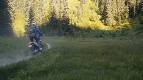 A group of dirt bikers ride through a mountain medow Stock Footage 93002634