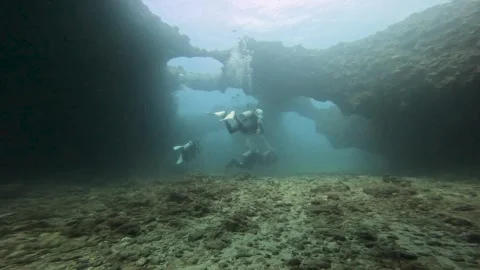 Group of divers exploring the seabed with large holes of rocks Stock Footage 284217971