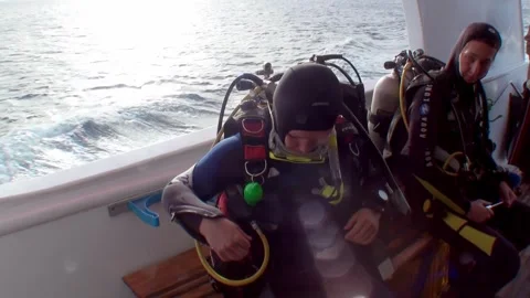 Group of divers prepare their gear for dive on yacht in front waves. Stock Footage 263836084