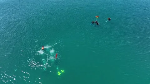 A group of divers surfaced. They swim with orange buoys in the open sea Stock Footage 203479991