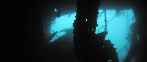 A group of divers swim in the murky water at a wreck Stock Footage 102467181