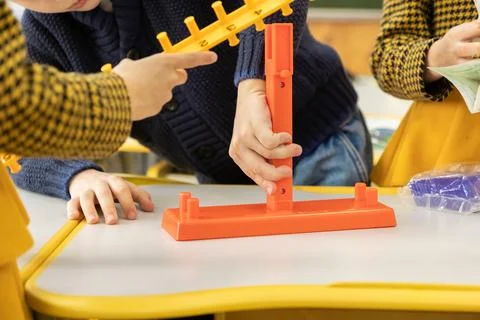 A group of diverse children are assembling a toy scale at a classroom desk .. Stockfoto's