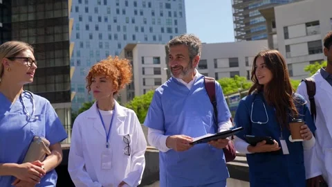 Group of diverse doctors and nurses walking outside hospital Stock Footage 338250528
