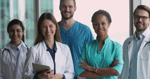 Group of diverse doctors wear uniforms pose in clinic office Stock Footage 253129309