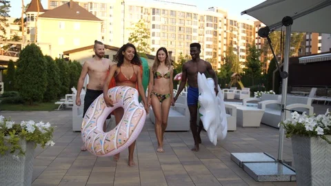 Group of diverse friends walking to pool at hotel Stock Footage 114975406