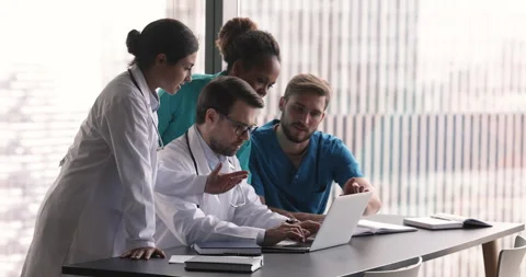 Group of diverse general practitioners engaged in teamwork using computer Stock Footage 253129566