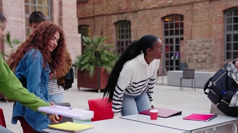 Group of diverse generation z students arriving together at table on campus Stock Footage 315881078
