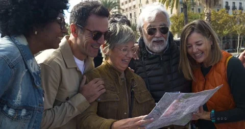 Group of diverse middle aged friends looking at a map during vacation in a city Stock Footage 255019697