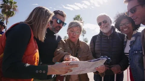Group of diverse middle-aged tourist people standing looking at travel map in Stock Footage 269509752