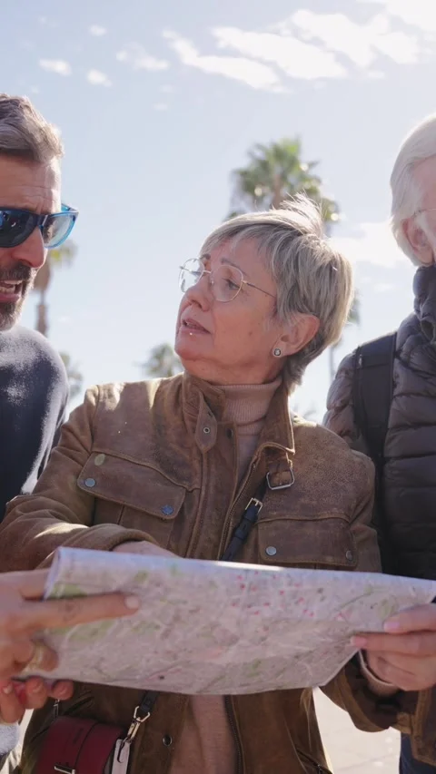 Group diverse middle-aged tourist people standing looking at travel map in hands Stock Footage 270254461