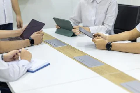 A group of diverse professionals sitting around a conference table, using d.. Stock Photos